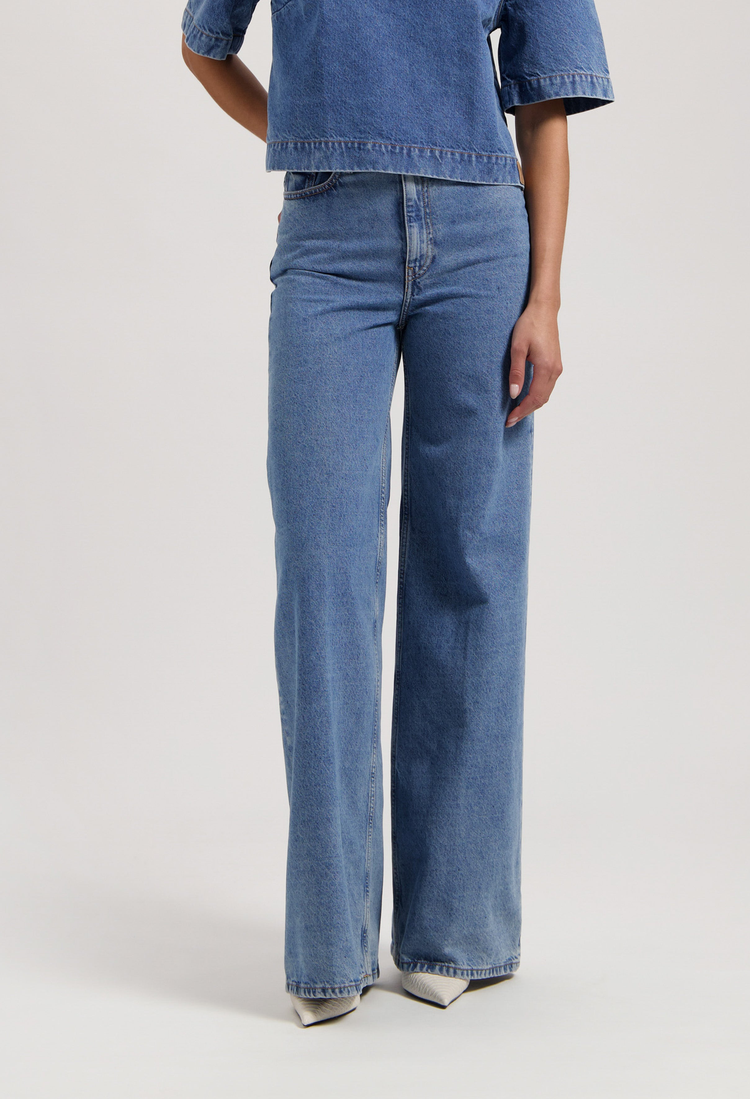 Wide-leg blue denim jeans paired with a denim short-sleeve top, showcasing relaxed fit and light wash style.