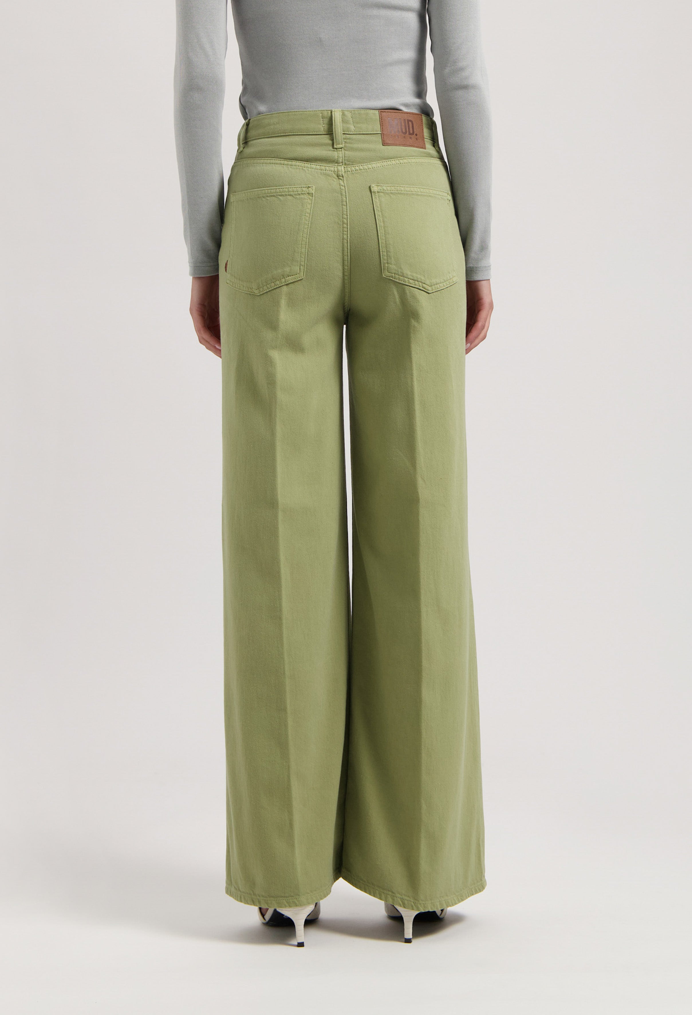 Wide-leg trousers in organic cotton, light green color, worn with a gray long-sleeve top, highlighting sustainable fashion.
