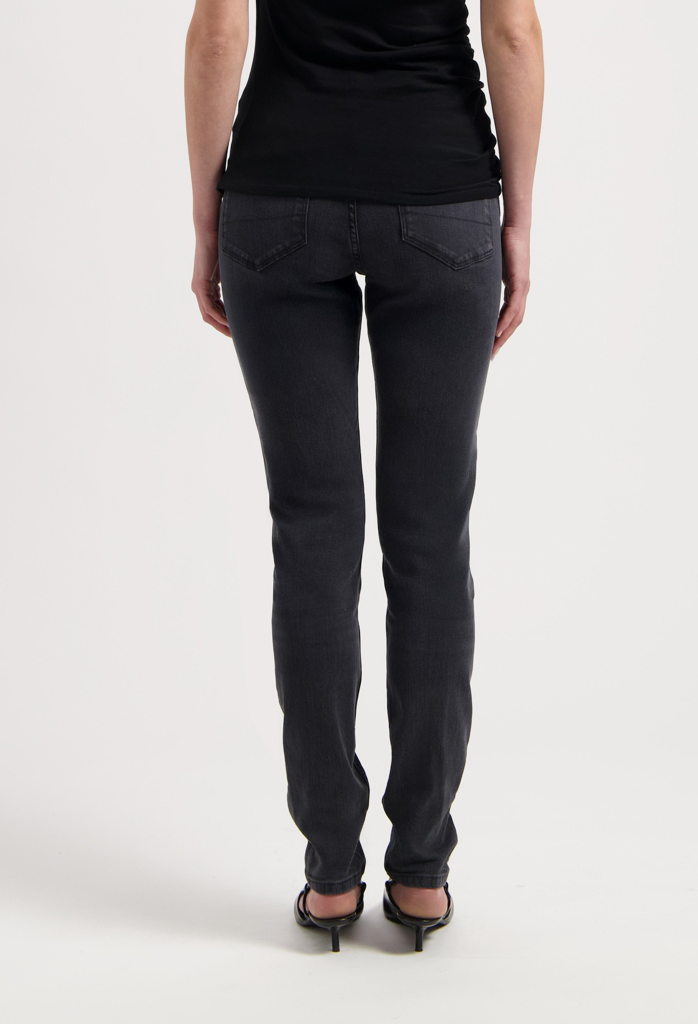 Black slim-fit jeans made from soft denim, showcasing rear view with decorative stitching and high heels for an elegant look.