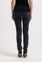 Black slim-fit jeans made from soft denim, showcasing rear view with decorative stitching and high heels for an elegant look.