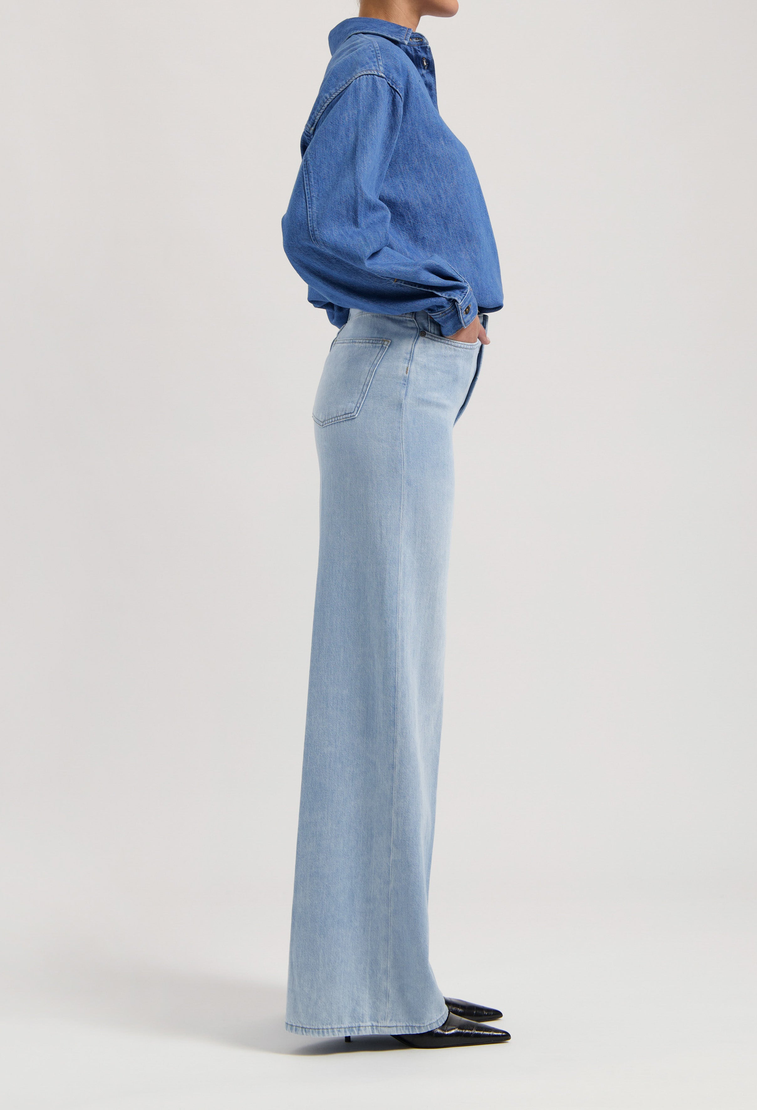 Wide-legged, light blue jeans paired with a dark blue denim shirt, showcasing a casual and stylish outfit.