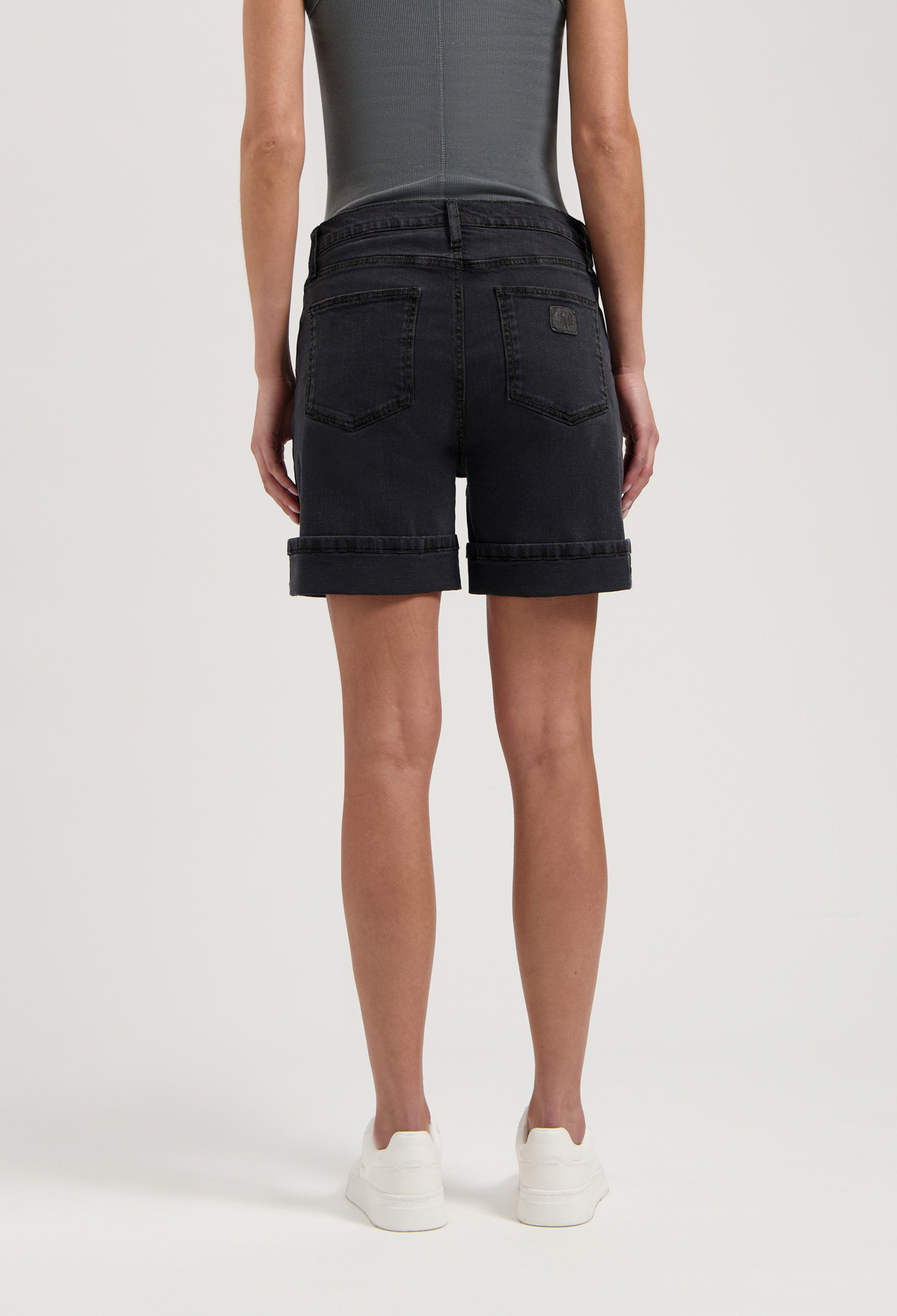 Comfortable dark denim shorts with cuffed hems, showcased in a back view, paired with a sleek gray sleeveless top.
