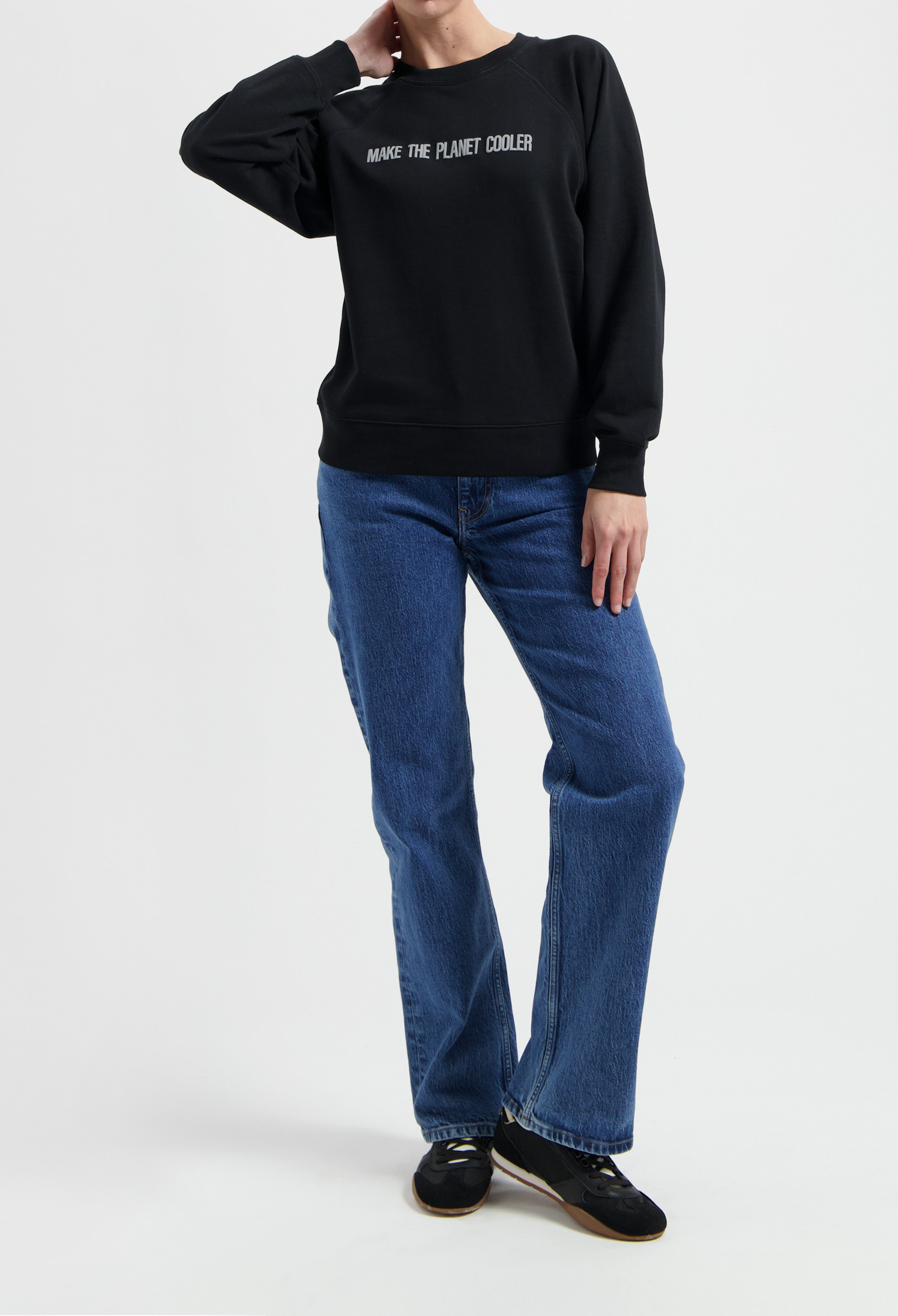 Casual outfit featuring a black sweatshirt with "Make the Planet Cooler" slogan, paired with classic blue jeans and black sneakers.