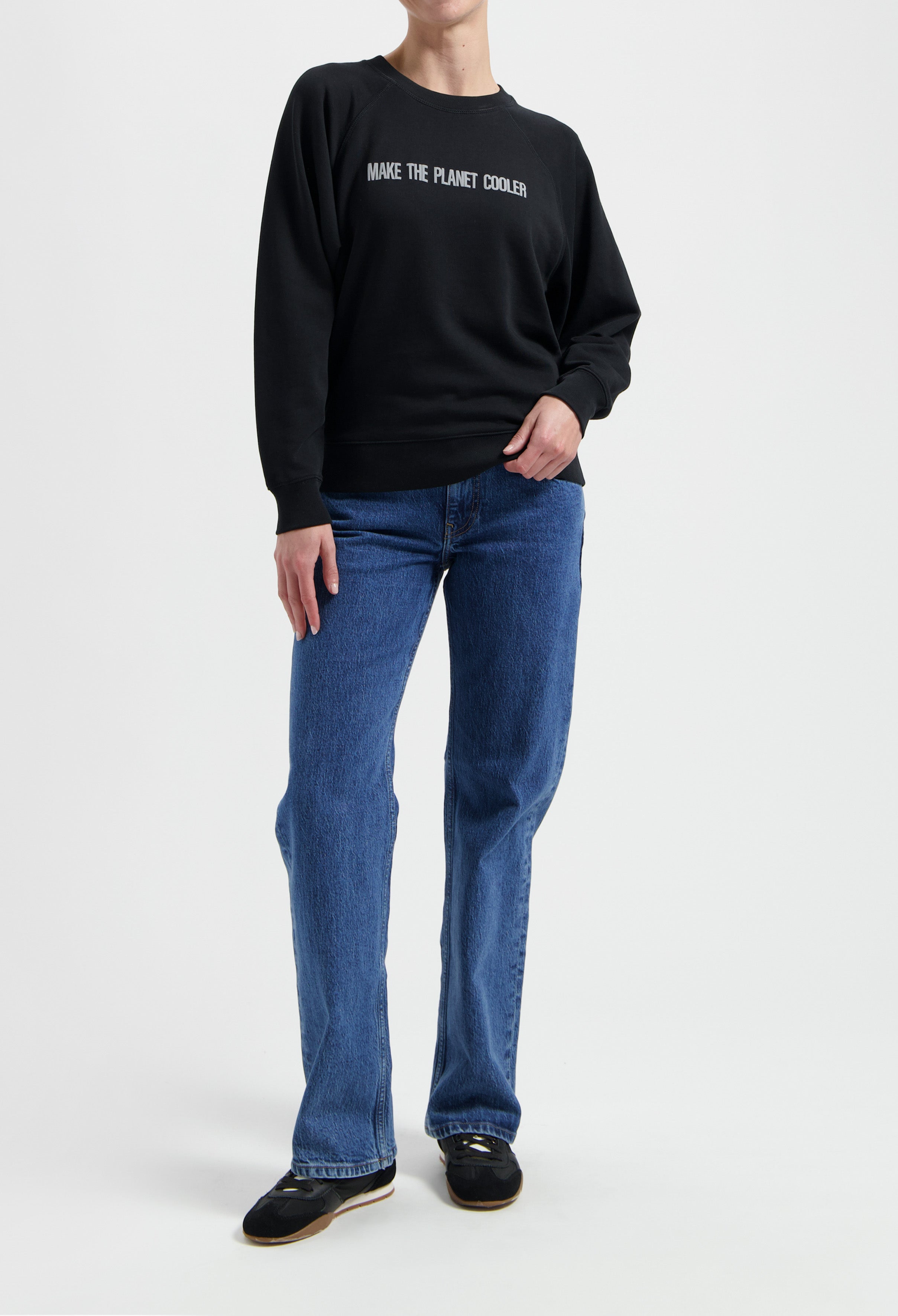 Black eco-friendly sweatshirt with "Make the Planet Cooler" message, paired with classic blue straight-leg jeans and black shoes.