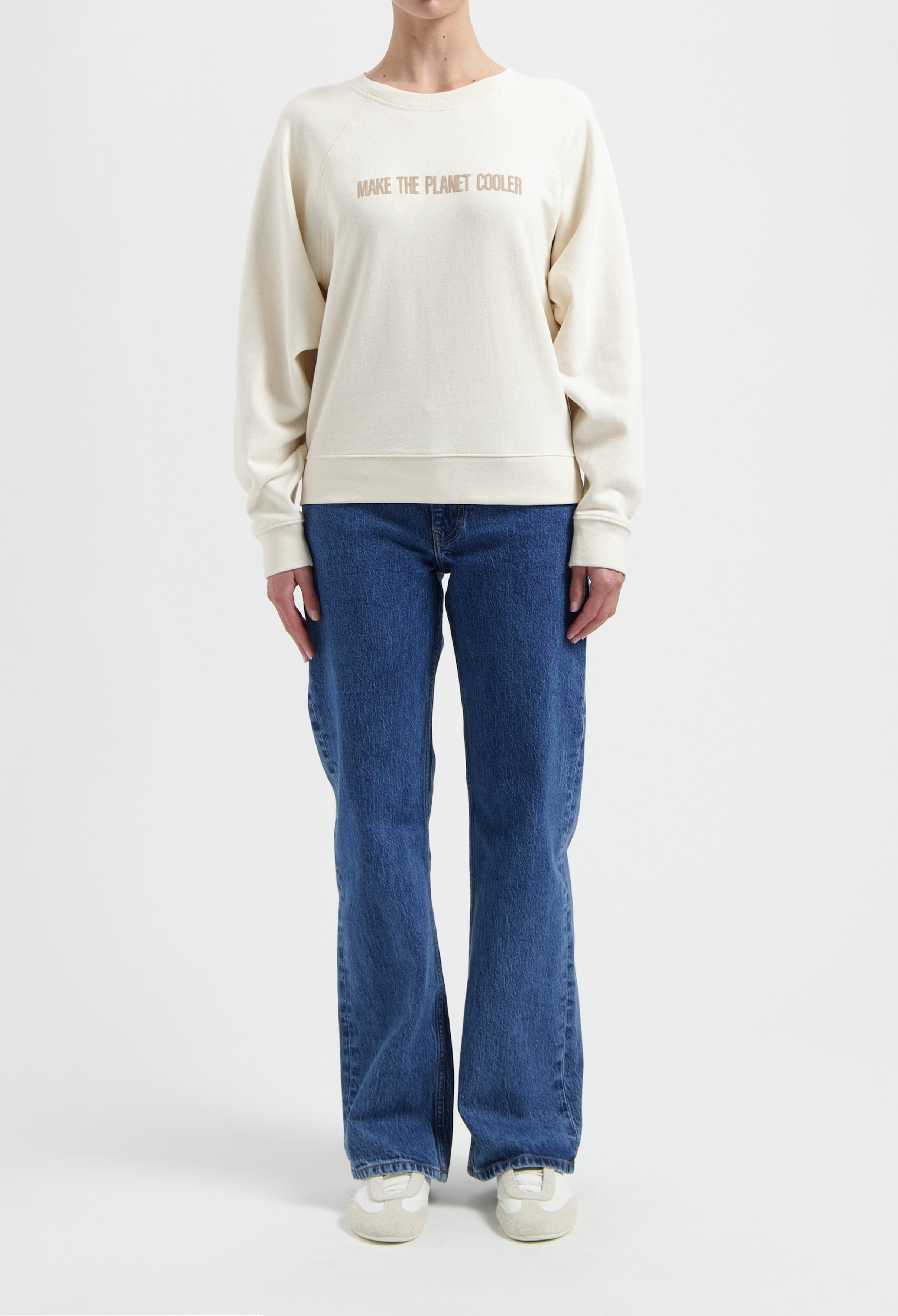 Cream-colored sweatshirt with "Make the Planet Cooler" text, paired with blue jeans and white sneakers, front view.
