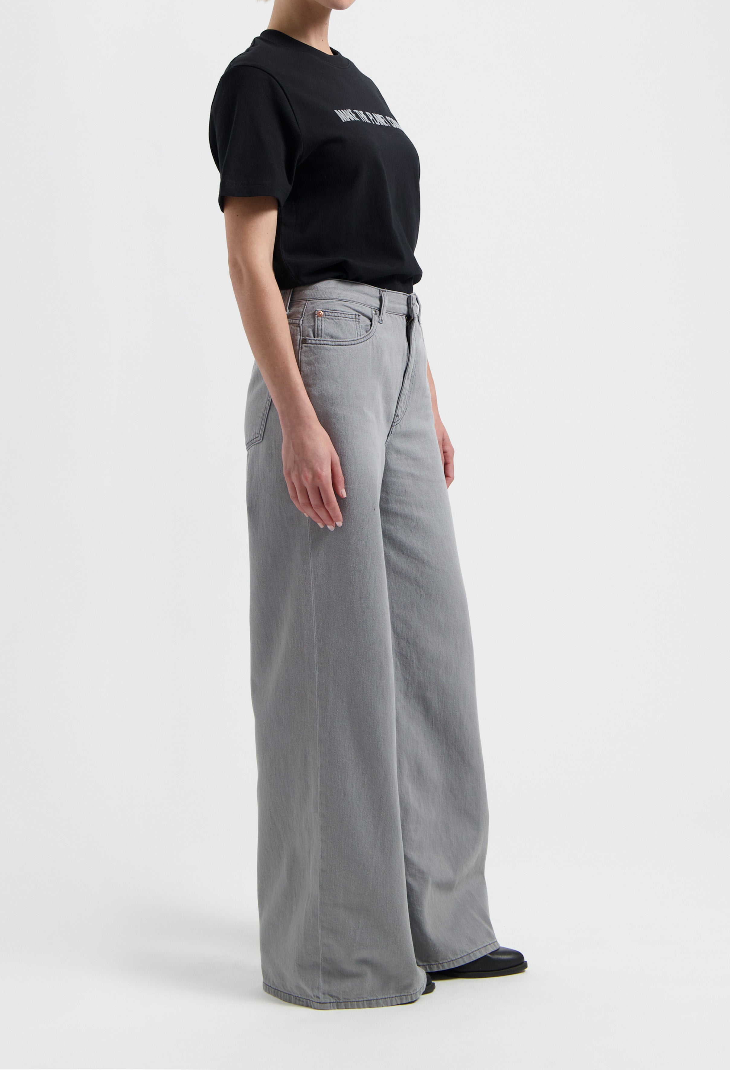 Sustainable MUD Jeans in beige, crafted ethically from organic cotton, paired with a casual gray T-shirt and sneakers.