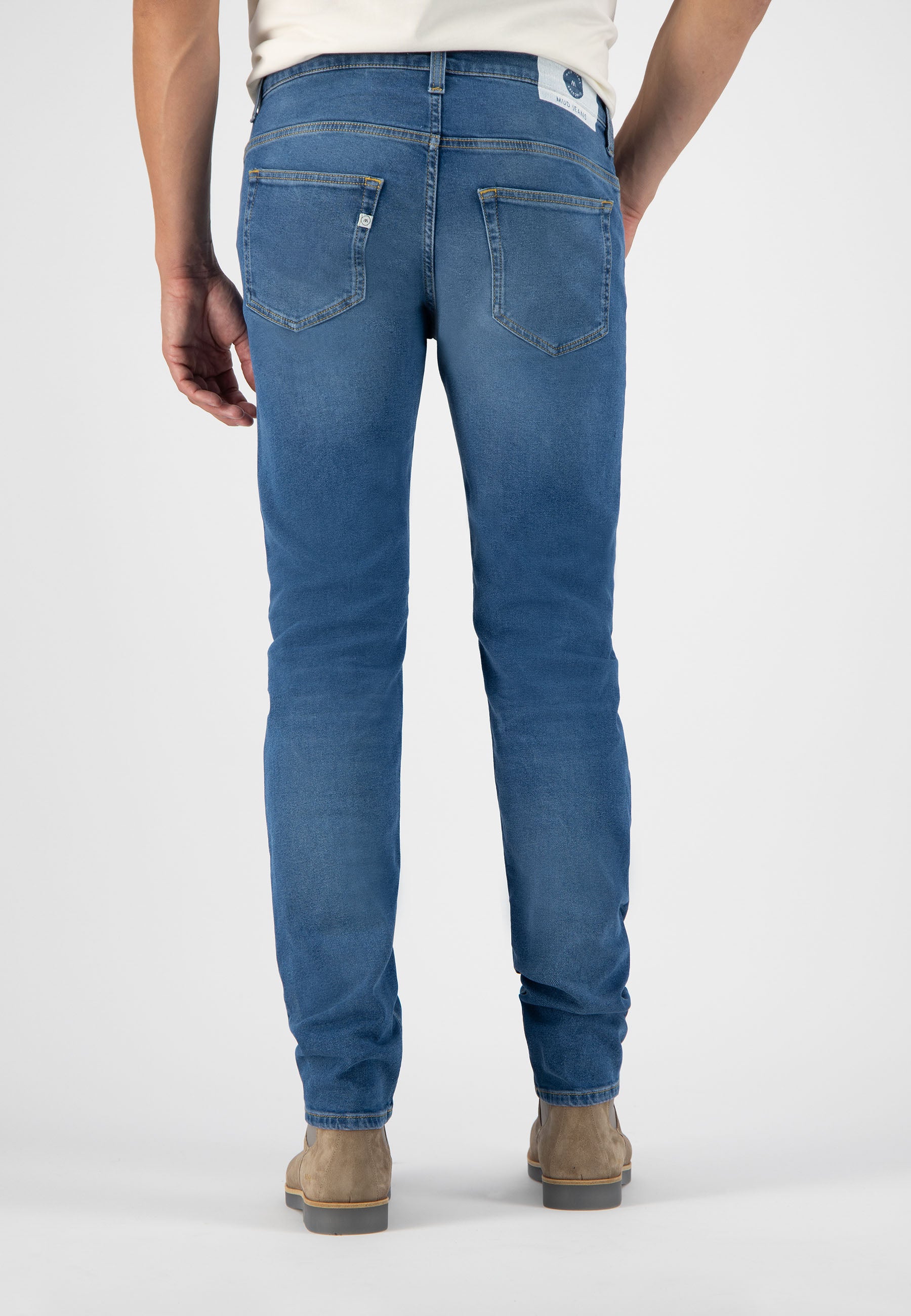 Sustainable MUD Jeans featuring dark blue cargo style, crafted ethically, worn with a black top and sneakers.
