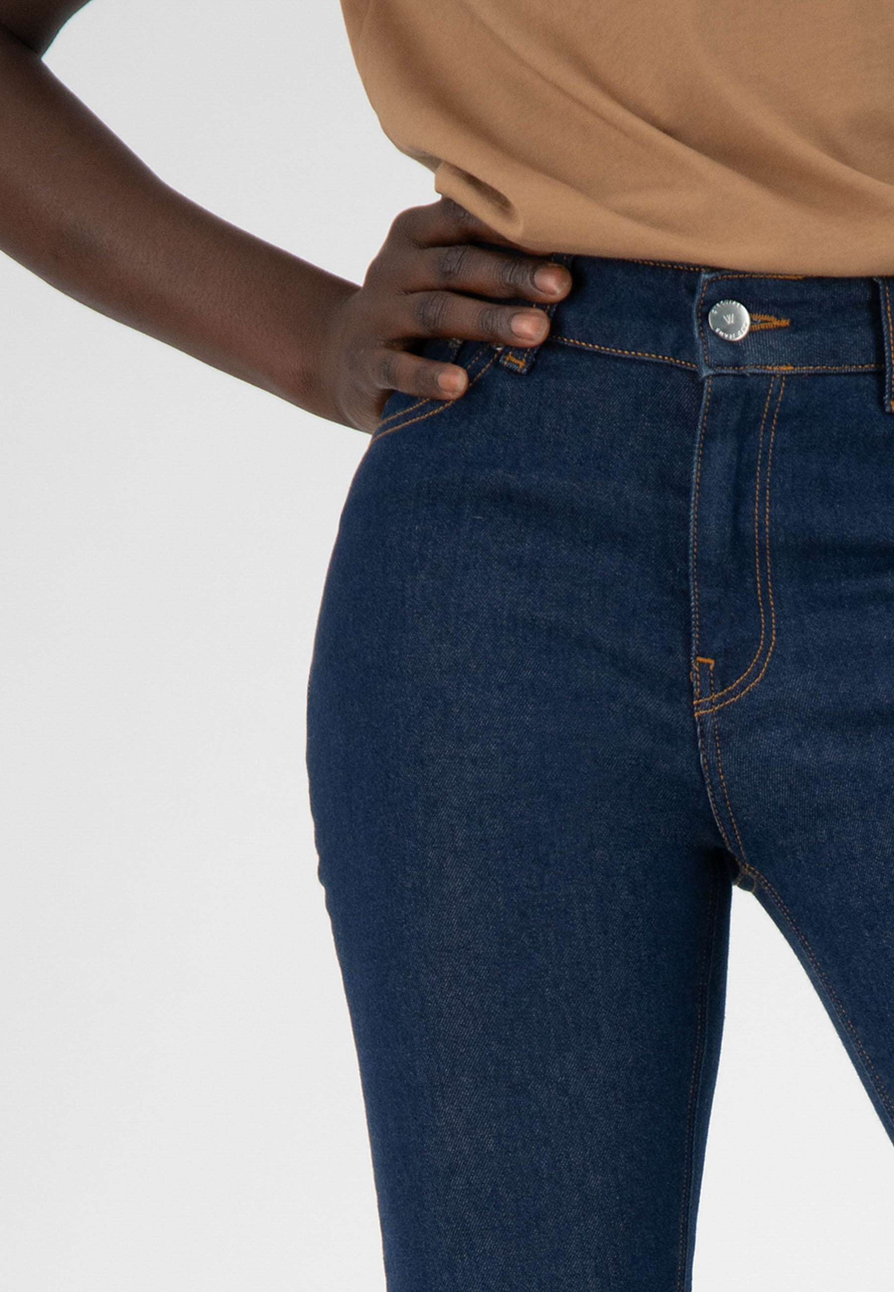 Dark blue high-waisted denim jeans with contrast stitching, paired with a beige top, showcasing casual chic style.