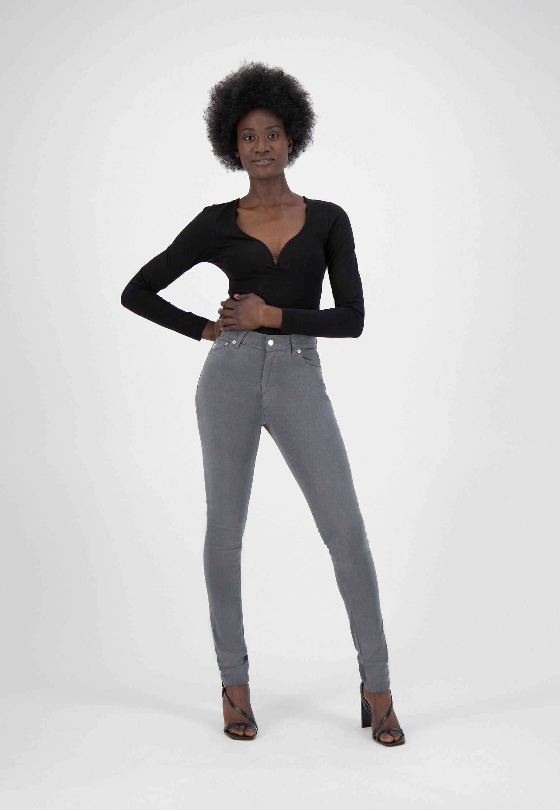 Stylish gray high-waisted skinny jeans paired with a sleek black V-neck long-sleeve top and open-toe heeled sandals.