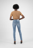 Model wearing light blue, high-waisted skinny jeans with a tan short-sleeve top, showcasing denim's back pocket details.