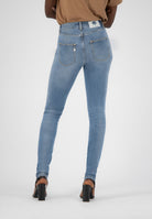 High-waisted light blue skinny jeans from MUD Jeans, showcasing back pockets and paired with black heels.