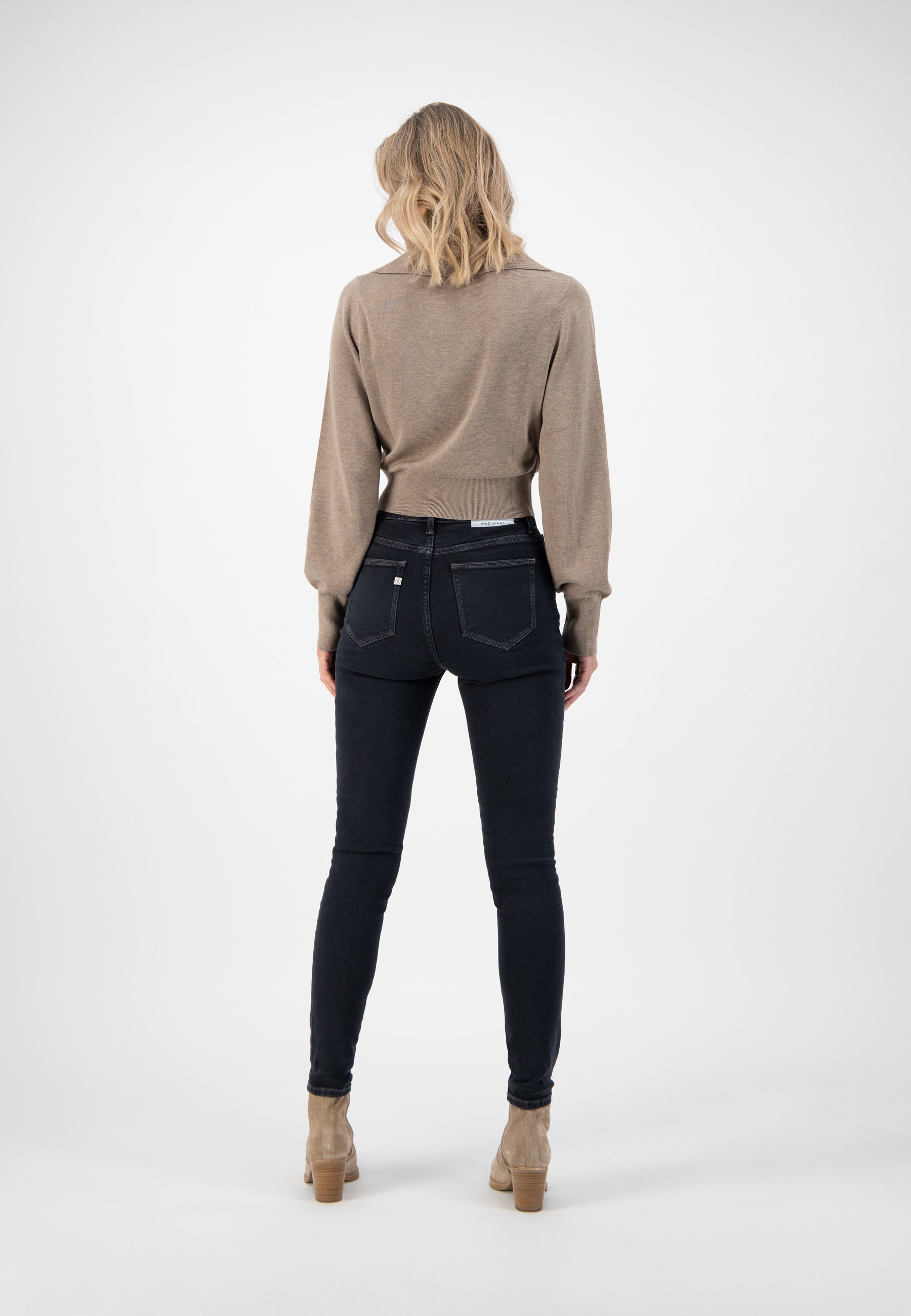 Women's outfit featuring a taupe wool sweater and black high-waist skinny jeans with beige suede ankle boots.