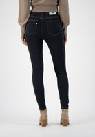 Back view of sustainable MUD Jeans, dark blue slim-fit denim, paired with taupe suede ankle boots and beige knit sweater.