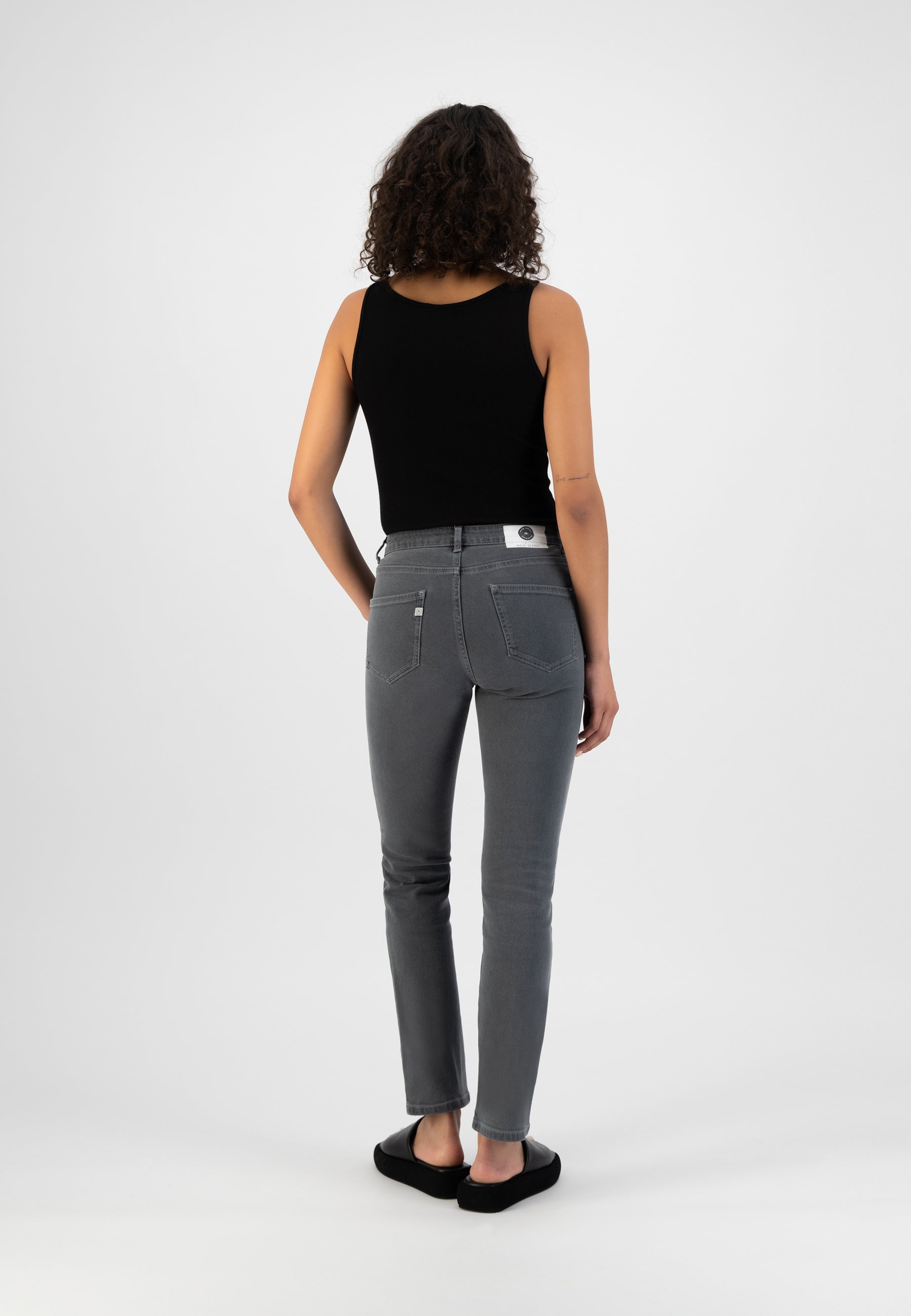 Stylish gray skinny jeans paired with a sleeveless black top, showcasing a modern casual look from the back view.