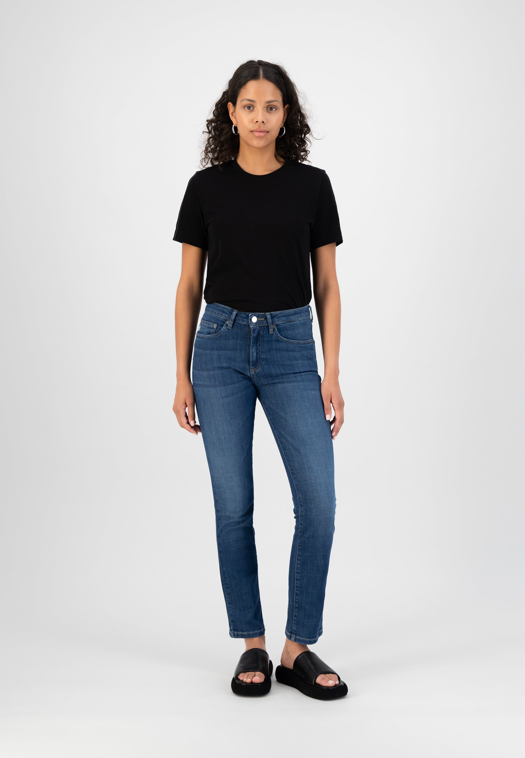 Casual outfit featuring slim-fit denim jeans paired with a sleek black T-shirt, styled with minimalist black sandals.