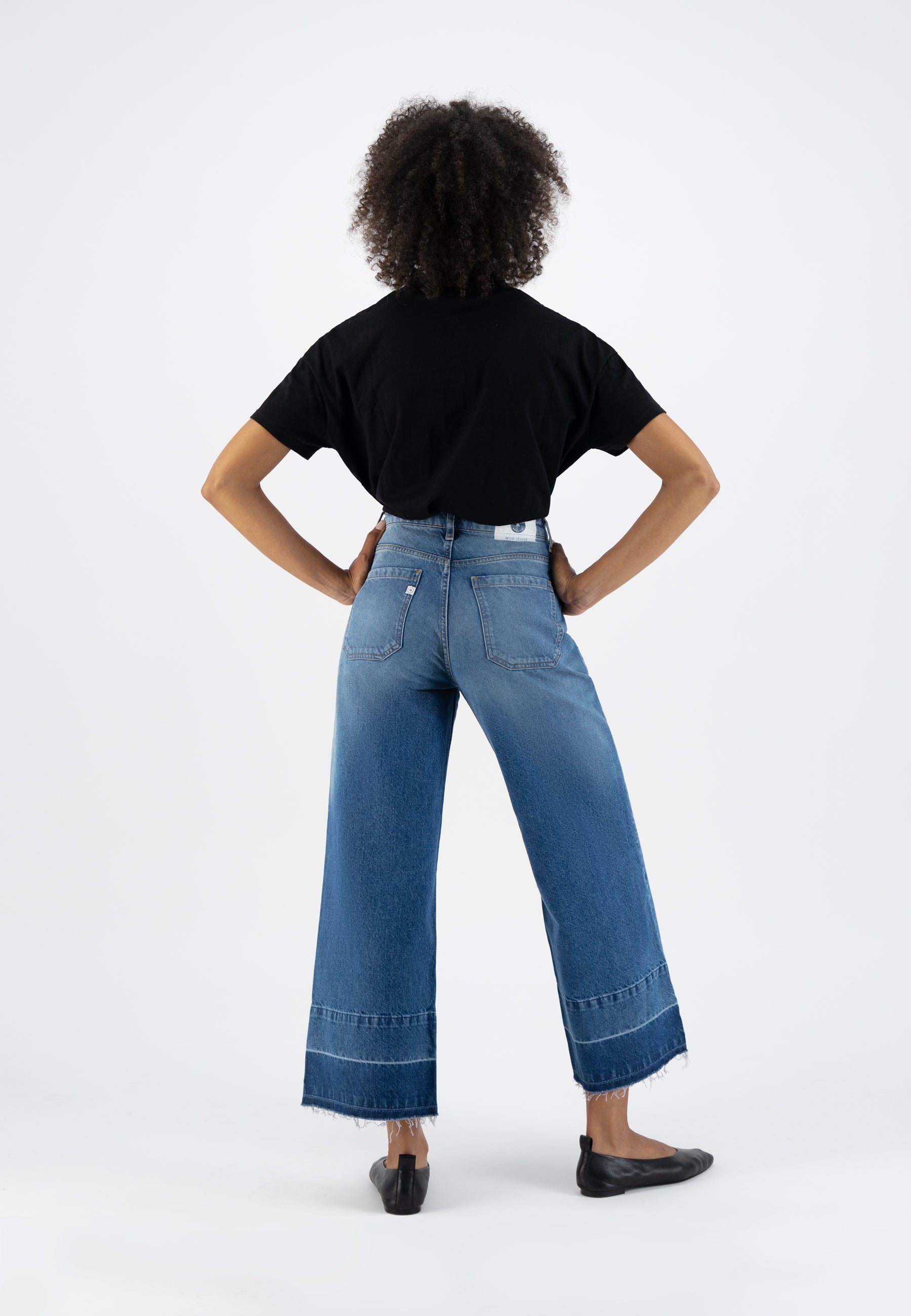 Wide-leg blue denim jeans paired with a black t-shirt, showcasing a casual and stylish back view of modern fashion.