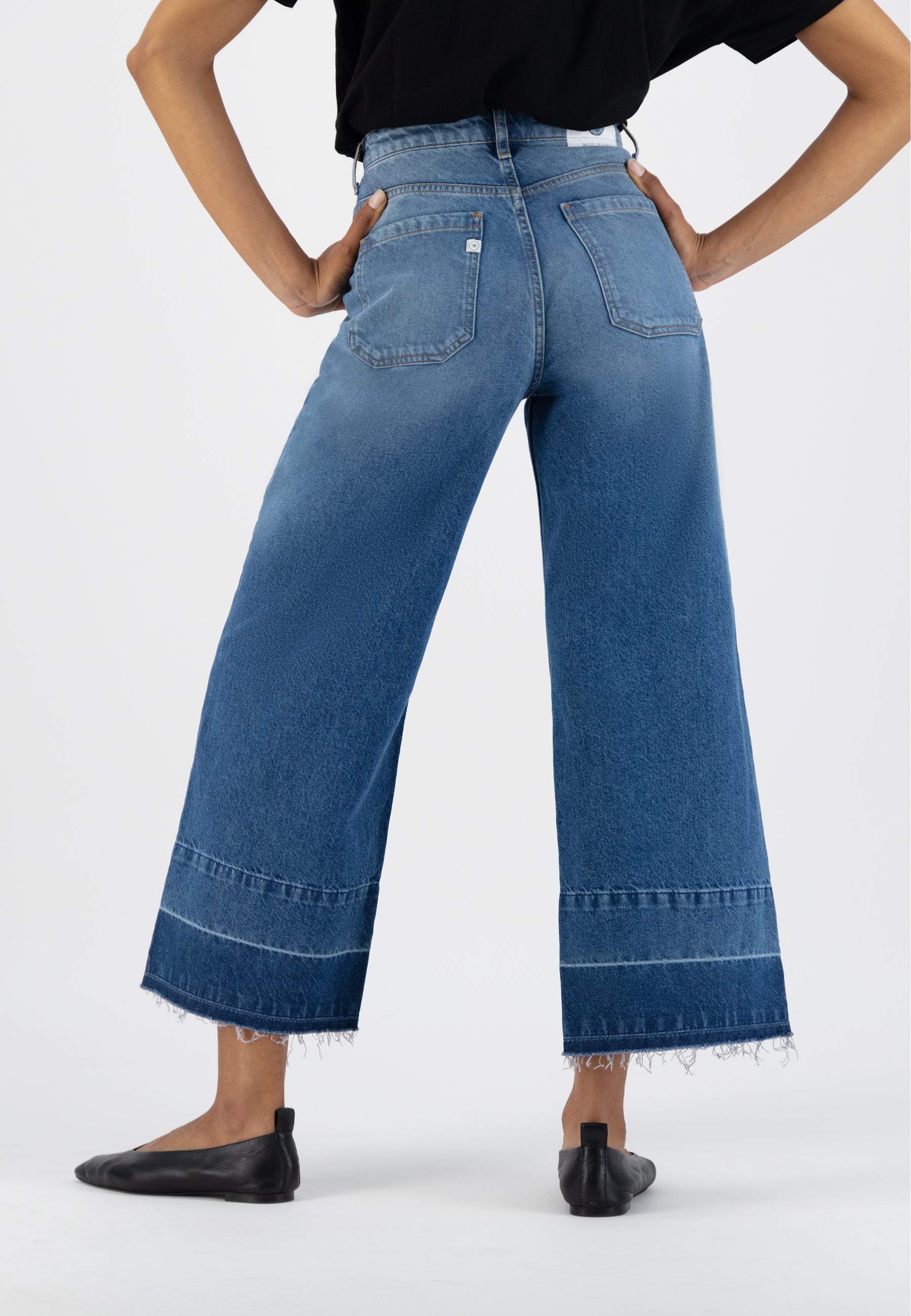 High-waisted blue denim culottes with frayed hem, worn with a black top, showcasing casual fashion for women.